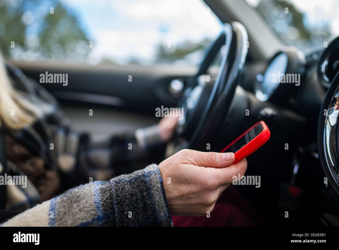 Woman car driver distracted by smartphone while riding auto in traffic, texting and reading messages Stock Photo