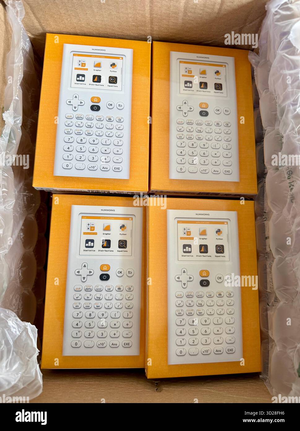 New graphing calculators in orange packaging inside a cardboard shipping box - Smartphone Captured Stock Image