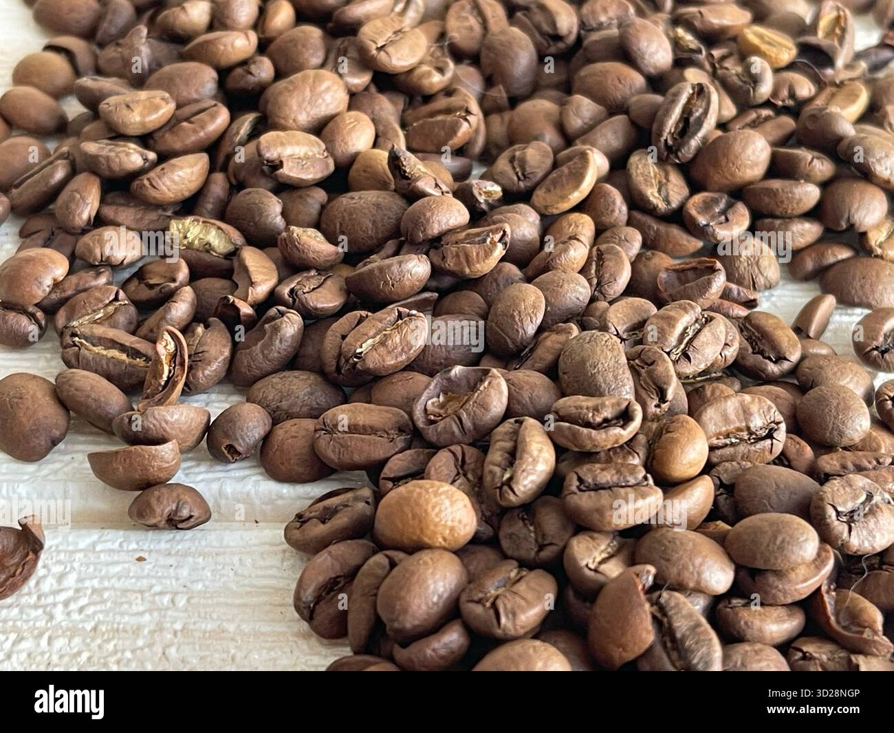 Freshly roasted coffee beans scattered on a wooden table, close-up macro shot. Stock Photo