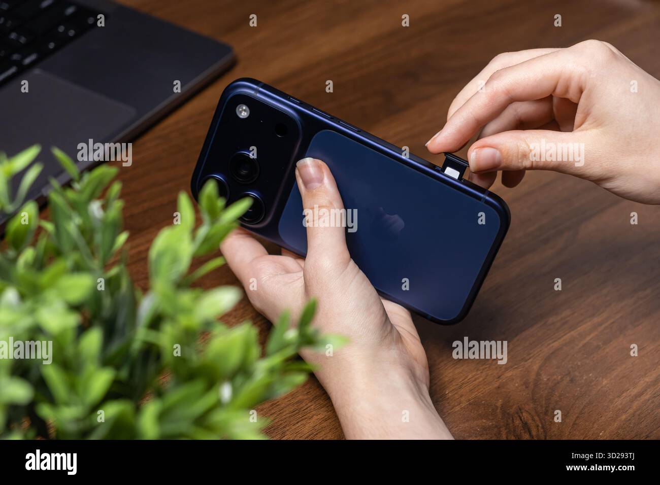 Poznan, Poland - October 16, 2025: Close-up of an iPhone 17 Pro in a hand, carefully inserting a nano SIM card into the side tray for network activati Stock Photo