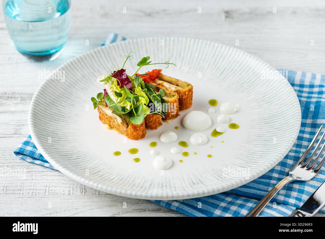 Crispy fish roulade with greens and white sauce drops Stock Photo - Alamy