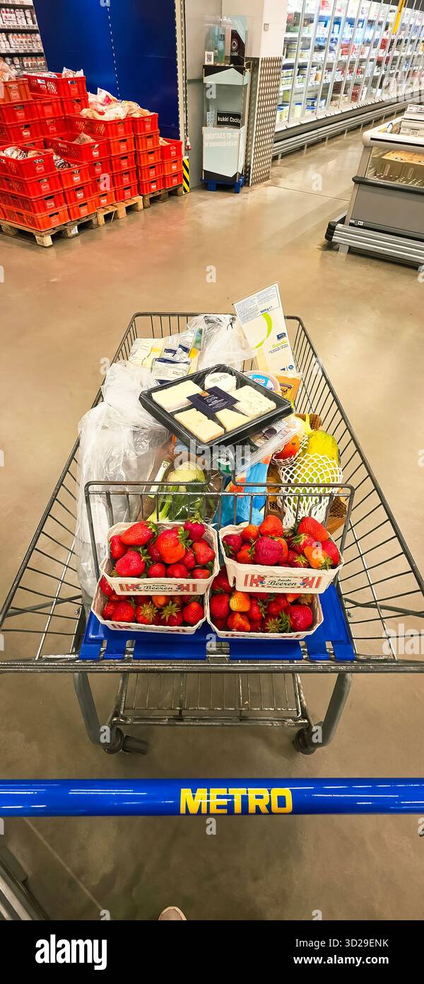 Belin, Germany - May 30, 2025: Shopping cart loaded with fresh fruits, groceries, and items in supermarket aisle. Hospital - Smartphone Captured Stock Image