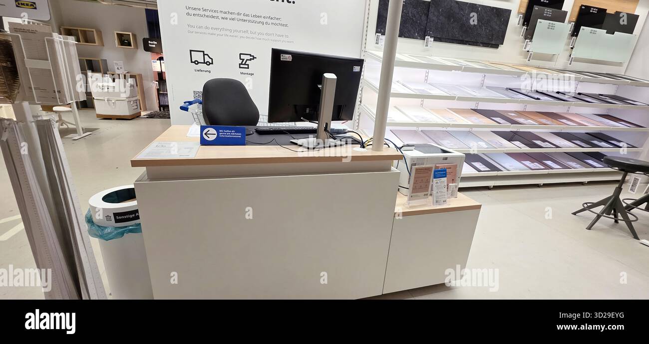 Berlin, Germany - May 05, 2025: Modern service counter features computer and display in retail store interior design. - Smartphone Captured Stock Image