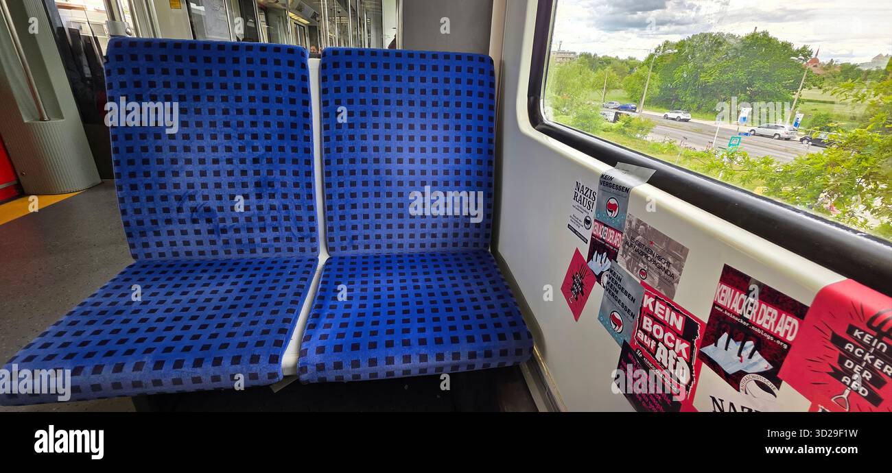 Berlin, Germany - May 08, 2025: Blue patterned seats in train car with window view of urban landscape outside. - Smartphone Captured Stock Image