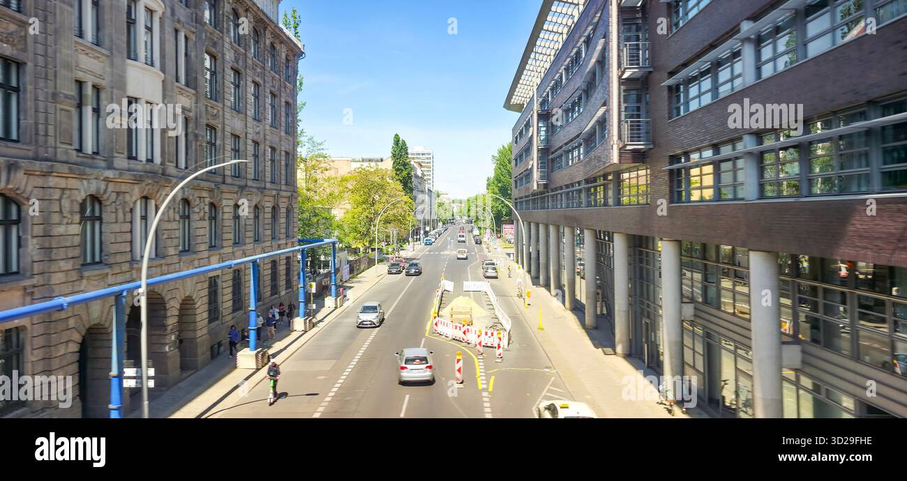 Berlin, Germany - May 13, 2025: Urban street scene features modern architecture, vehicles, and trees lining the road. - Smartphone Captured Stock Image