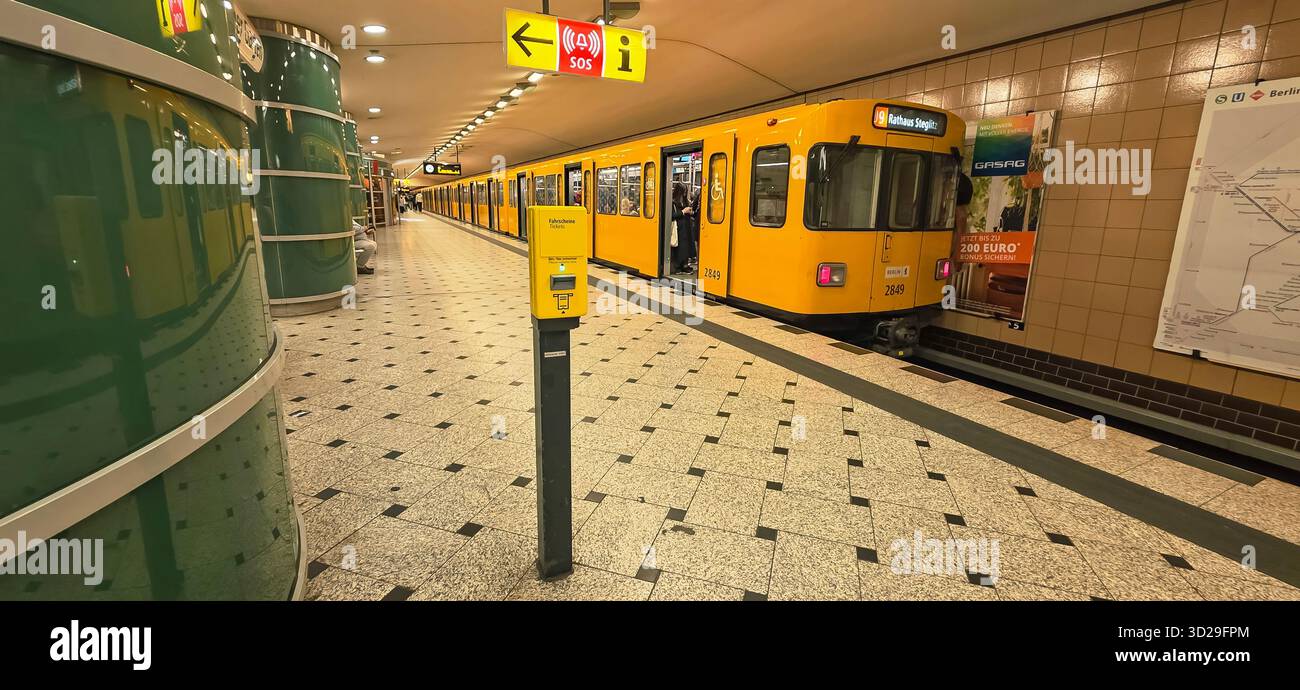 Belin, Germany - May 19, 2025: Yellow subway train is waiting at station with modern architecture and clear signage. - Smartphone Captured Stock Image