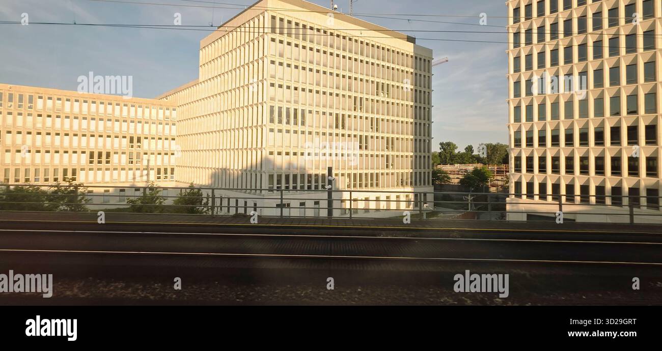 Berlin, Germany - June 13, 2025: Modern architectural structures feature glass facades beside railway tracks. - Smartphone Captured Stock Image