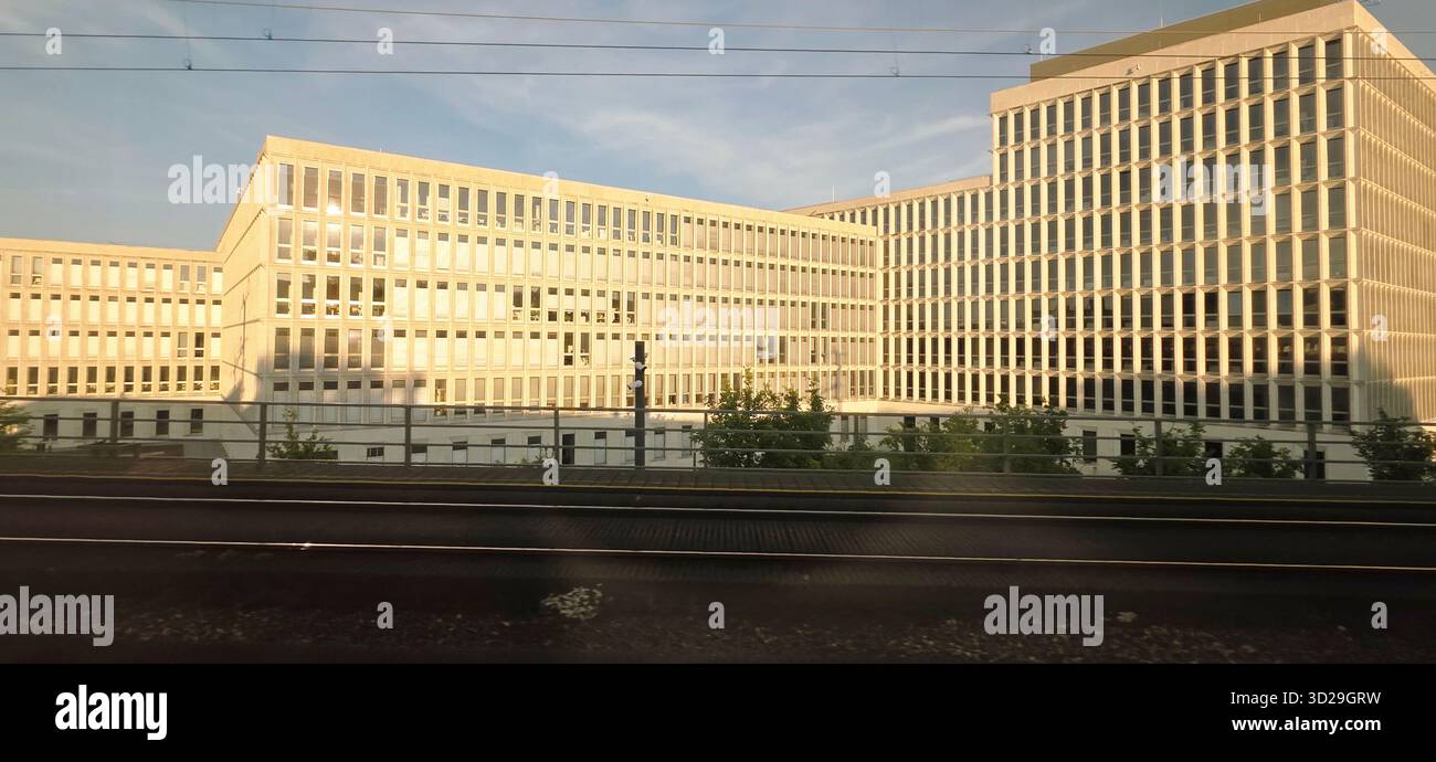 Berlin, Germany - June 13, 2025: Modern architectural structure features a glass facade and greenery surrounding the area. - Smartphone Captured Stock Image