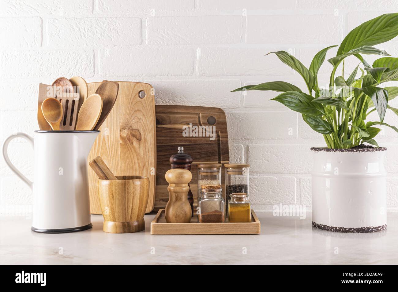 Beautiful kitchen background with spice storage area, cutting wooden boards, green plant in a chic indoor pot. white brick wall.. Front view Stock Photo