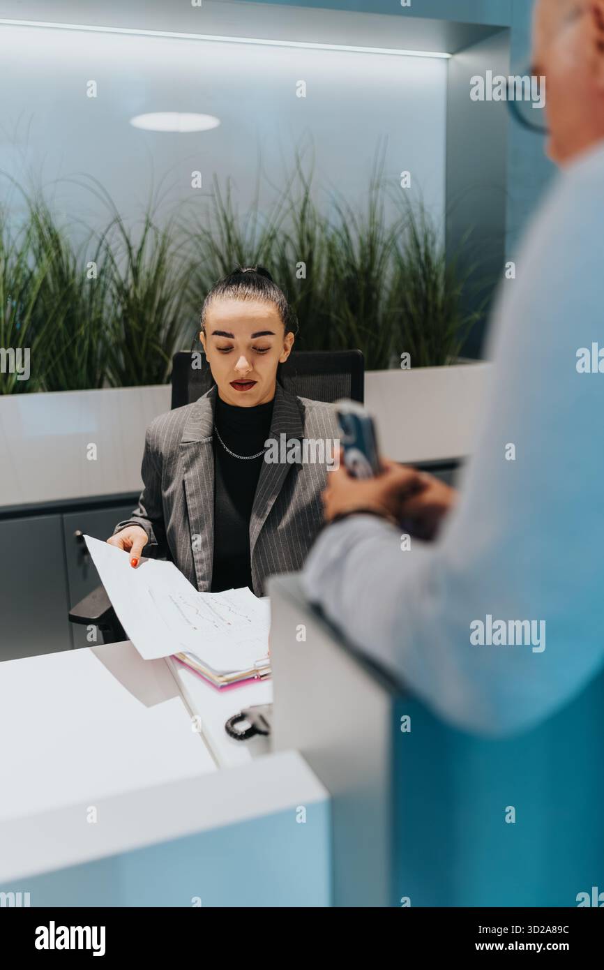 Professional woman at a reception desk reviewing documents for a client ...
