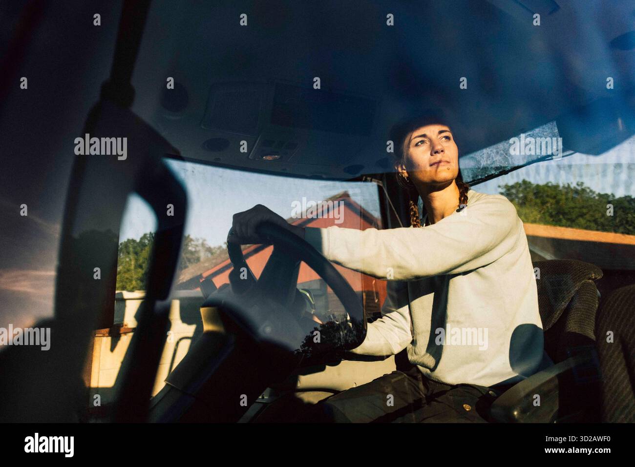 Female farmer looking away while driving tractor in farm Stock Photo ...