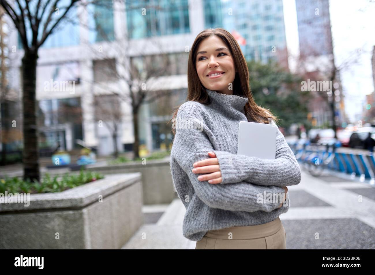 Young happy busy business woman standing in city using digital tablet. Stock Photo