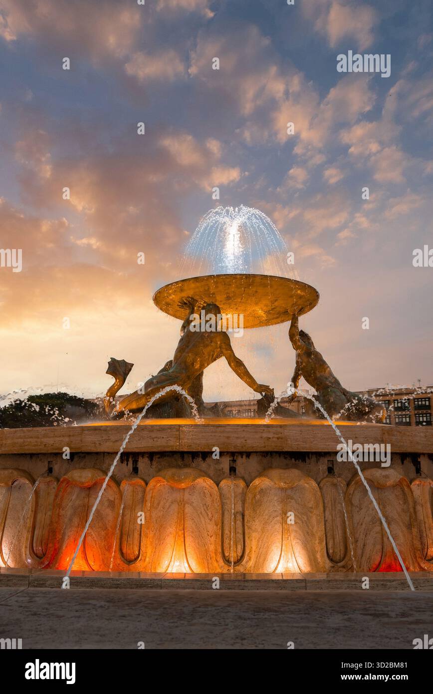Triton Fountain at Valletta entrance with lit bronze figures at dusk Stock Photo