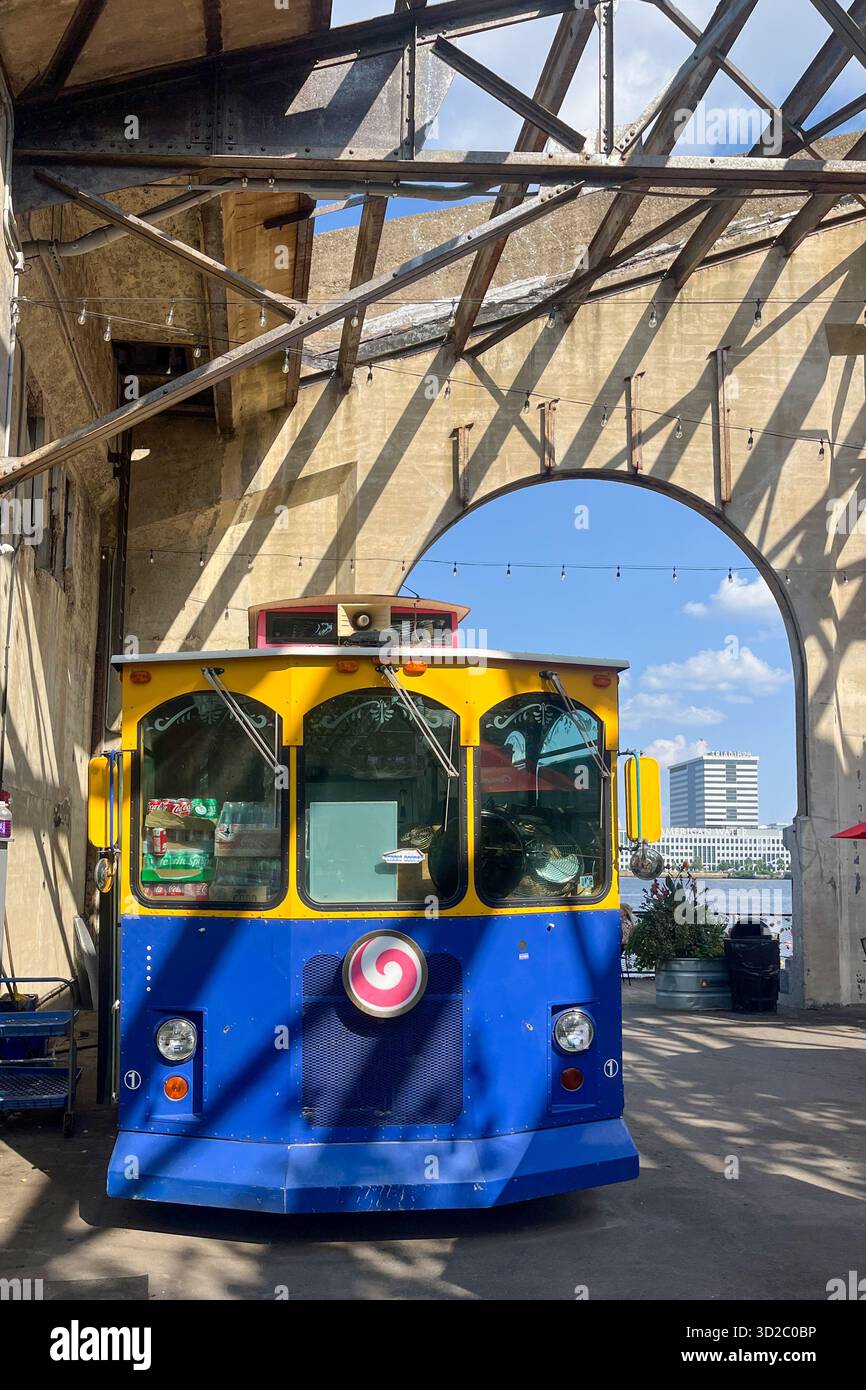 A blue and yellow trolley is parked in front of a building. The trolley ...