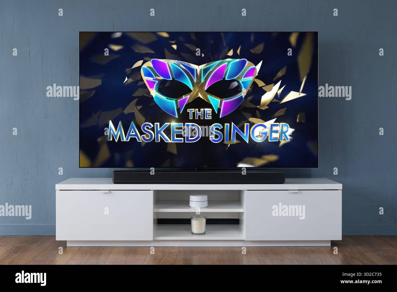 A widescreen OLED television showing the intro scene to the TV series The Masked Singer, seen in a contemporary living room. Stock Photo