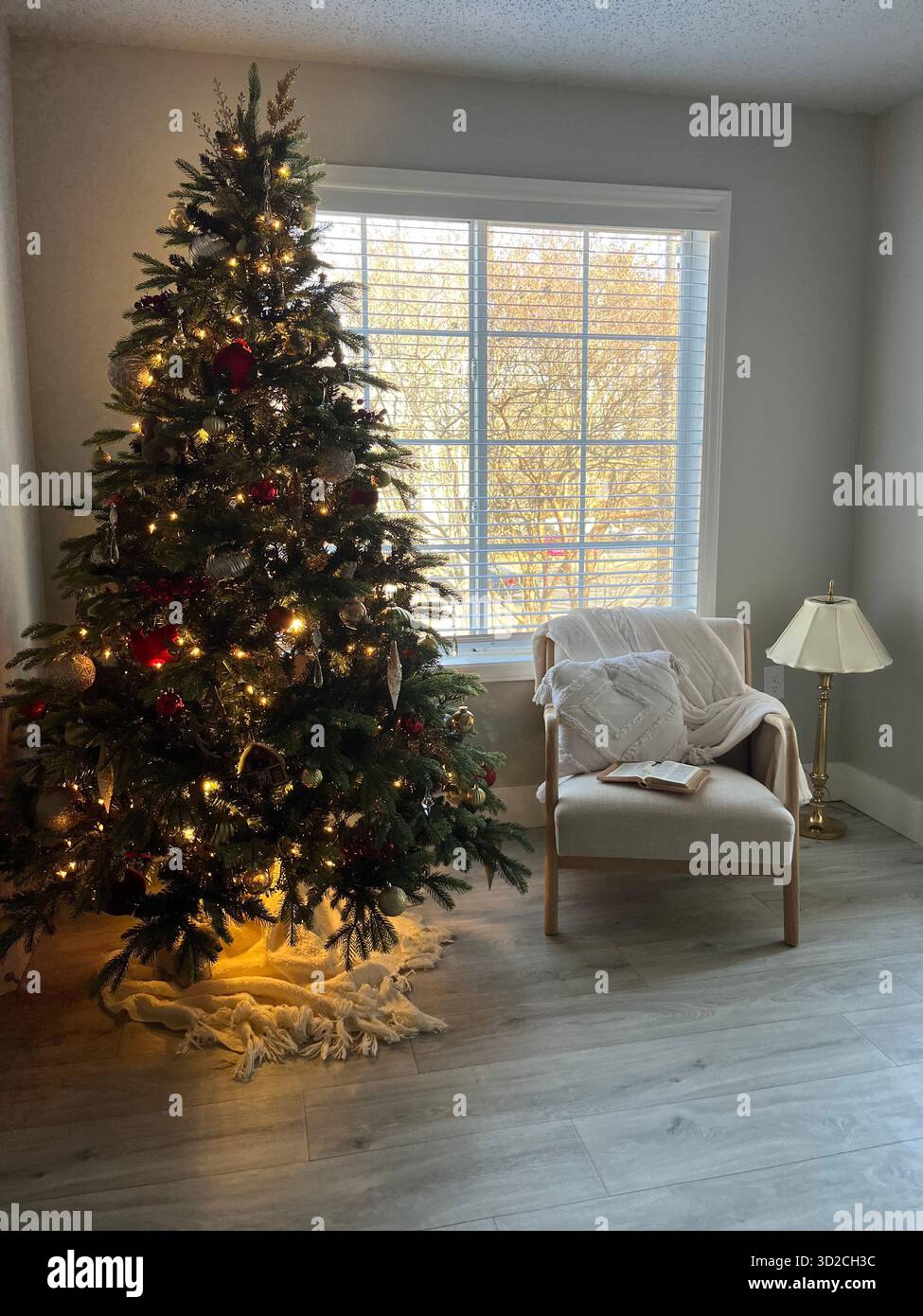 A cozy New Year's interior with a decorated Christmas tree, an armchair, a blanket, and a cup of coffee by the window - Smartphone Captured Stock Image