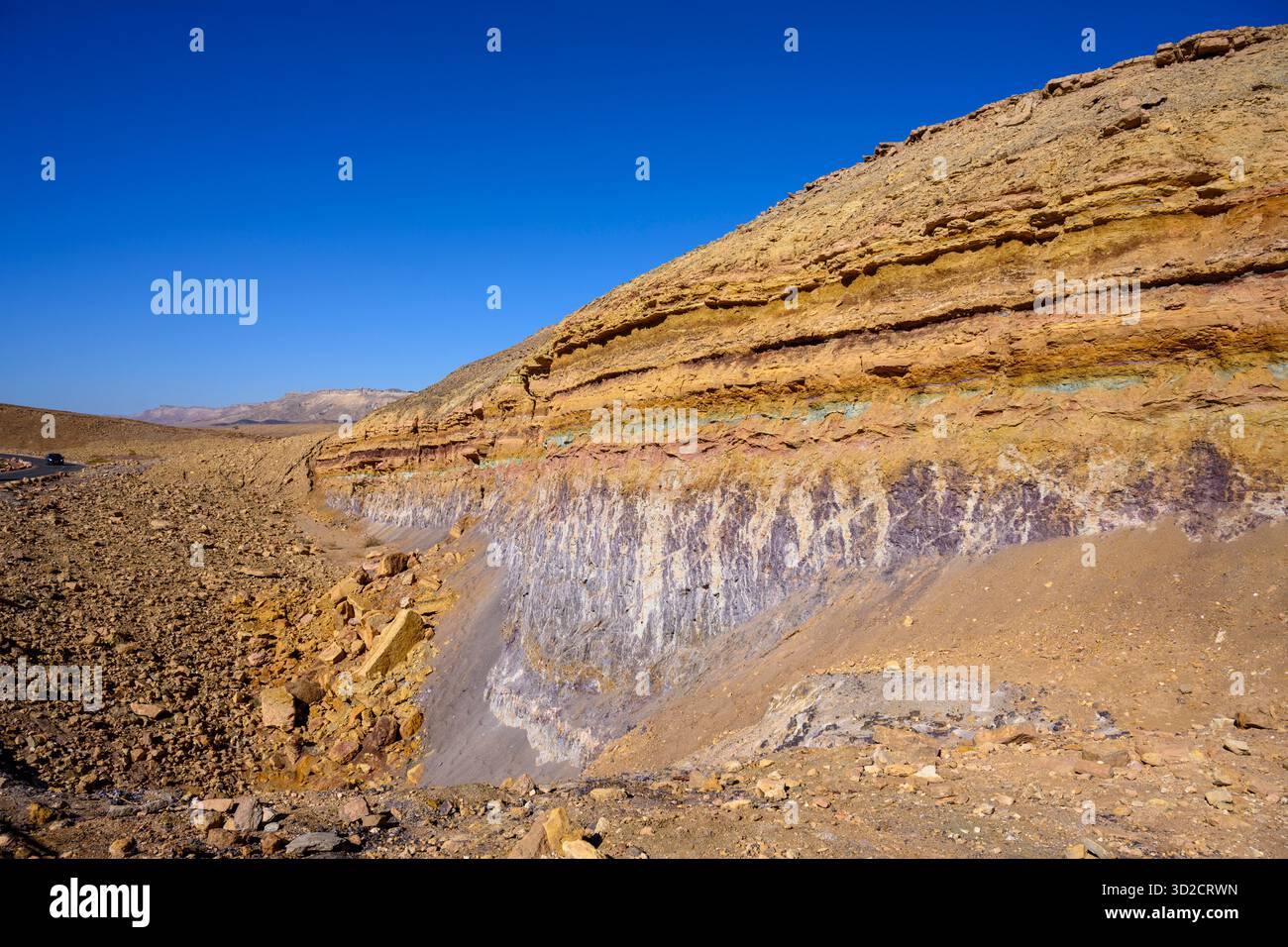 Rock layers exposed in a mine. The layers are: Ardon Formation: Brown limestone and marlstone exposed at the top of the mine wall, with intervening layers of green and chocolate-coloured clay and remains of fossilised soils. Mish'hor Formation (flint-clay): Purple and white mottled clay layers at the bottom of the wall. Mohila Formation: Exposed south of the path. Dark brown limestone beneath the Mish'hor Formation. Stock Photo