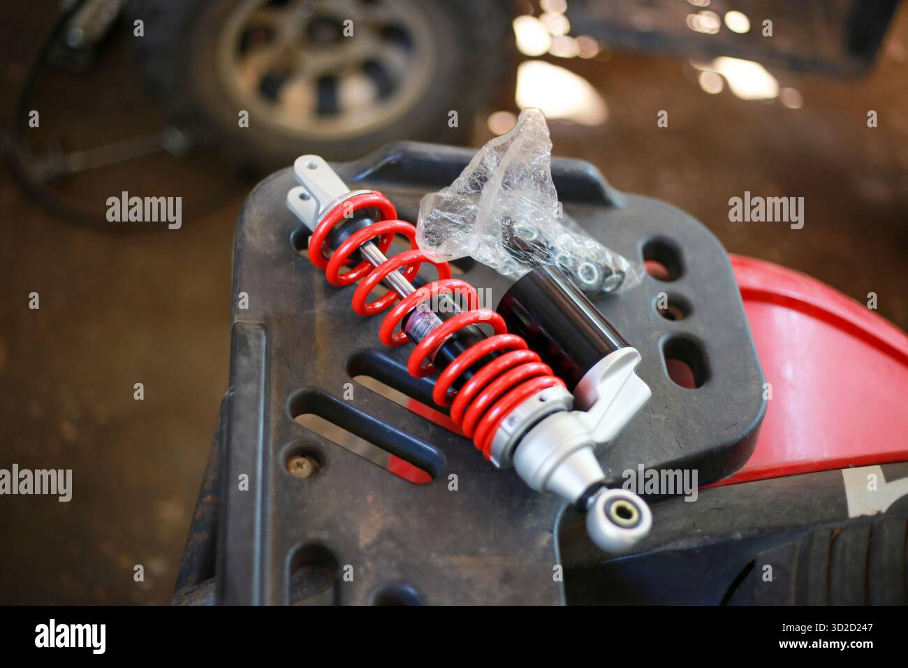 New red motorcycle gas shock absorber in a motorcycle repair shop to modify and install on an ATV. Stock Photo