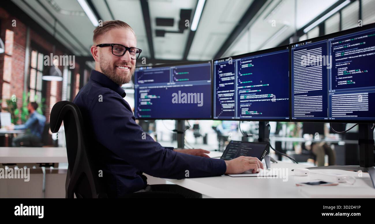 The Happy Coder: Man Thriving In Tech With Multiple Screens. Stock Photo