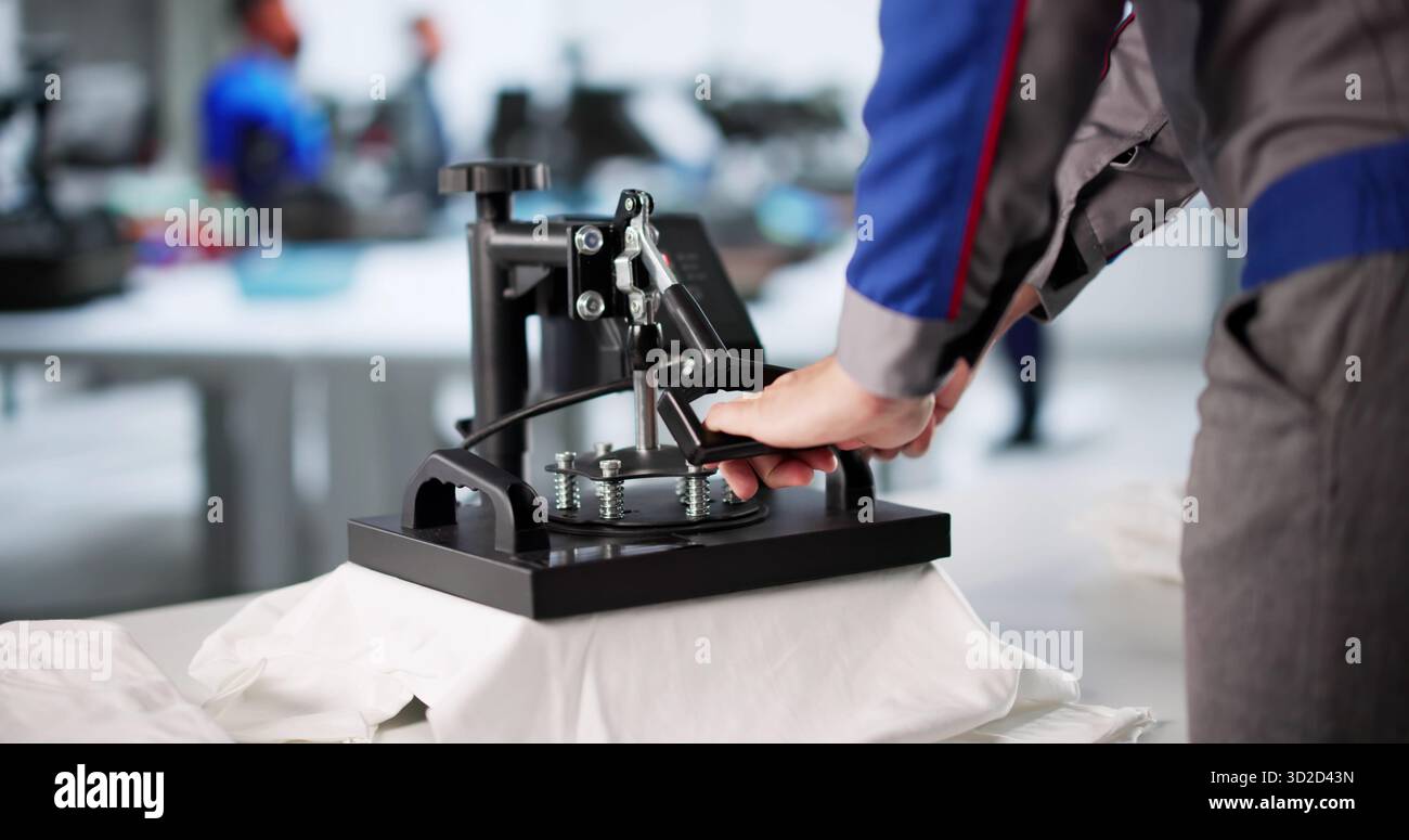 Young Man Designs Custom T-shirt Graphics Using Digital Printing Machine. Stock Photo