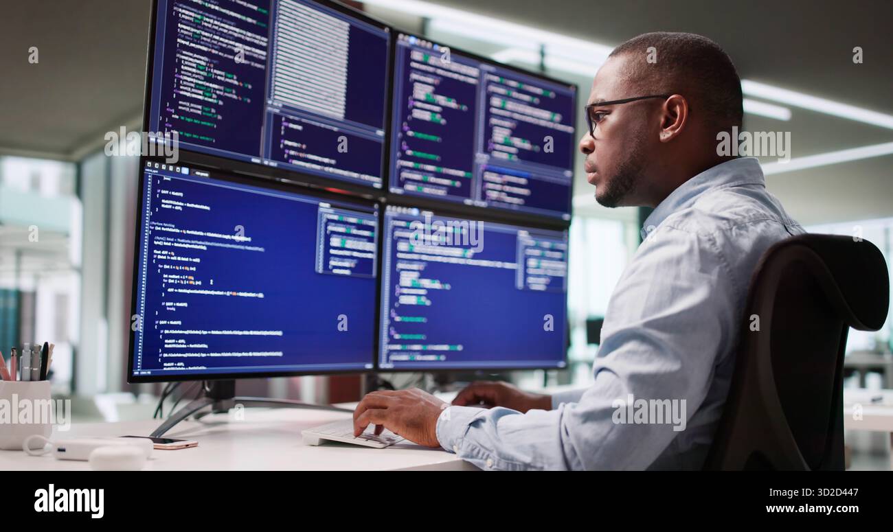 Leading African American Engineer Codes Software On Multiple Screens At Office Stock Photo