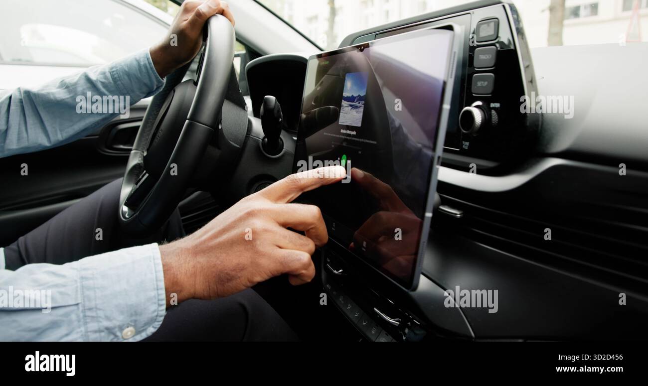 Black Man Using Touchscreen Infotainment Panel In Modern Car Interior. Stock Photo