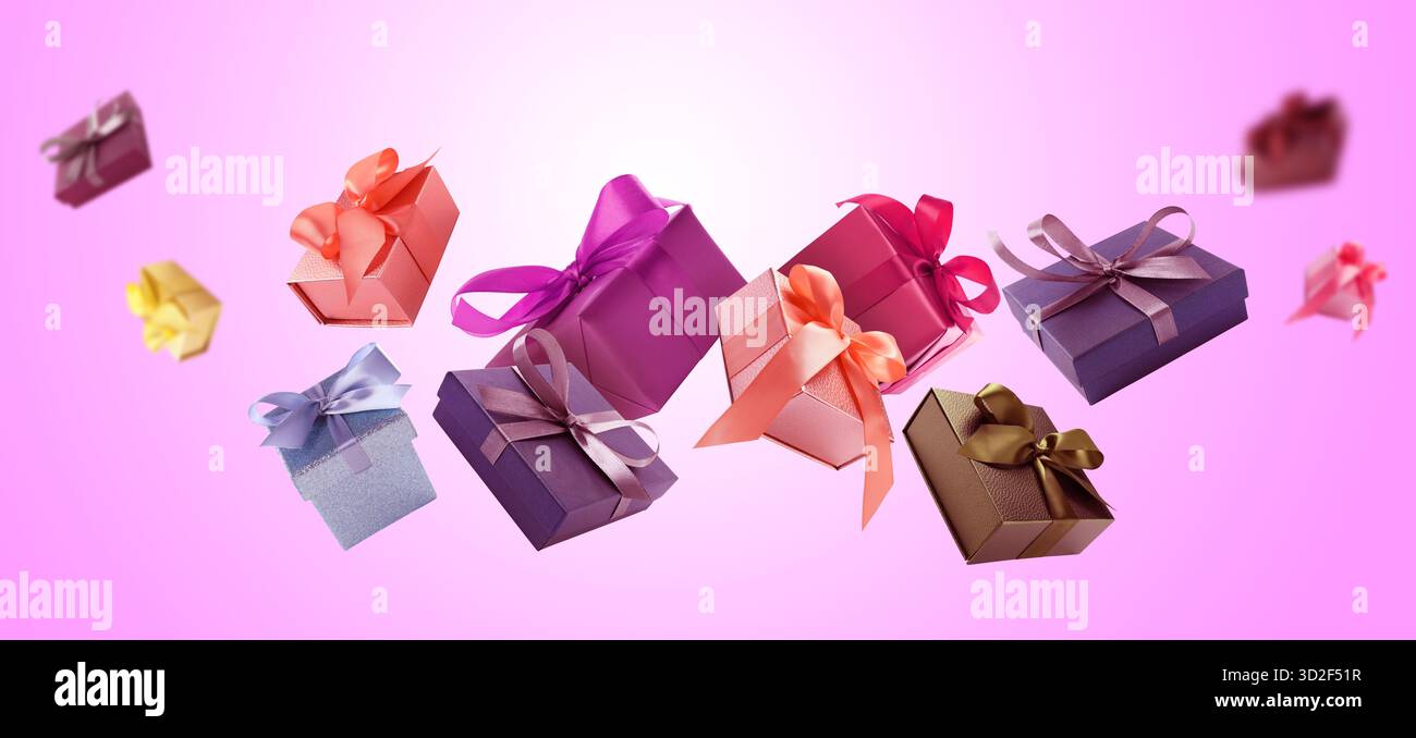 Gift boxes flying in air on magenta gradient background Stock Photo