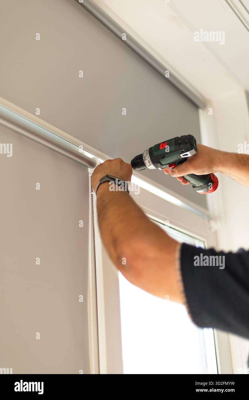 Process of installing window blinds using screwdriver and tools indoors. Stock Photo
