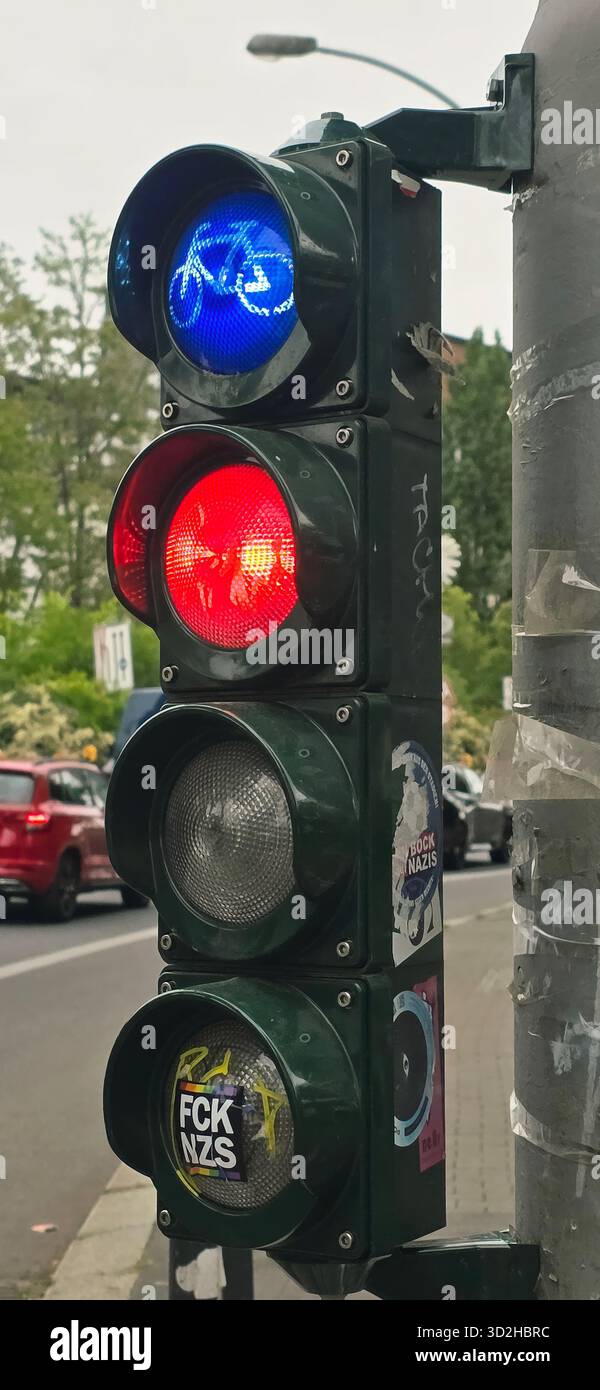 Belin, Germany - May 19, 2025: Traffic light displays blue, red, and green signals in a busy urban street environment. - Smartphone Captured Stock Image
