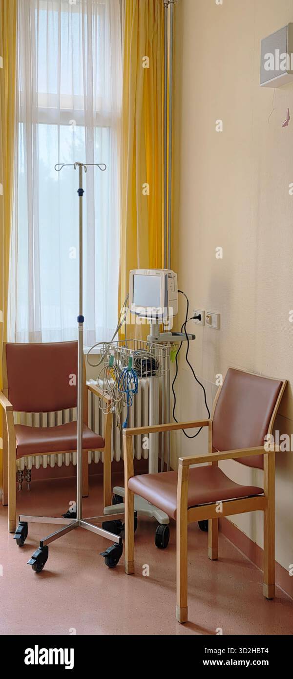 Berlin, Germany - June 16, 2025: Hospital room features an IV stand and two chairs beside a large window with sunlight. - Smartphone Captured Stock Image