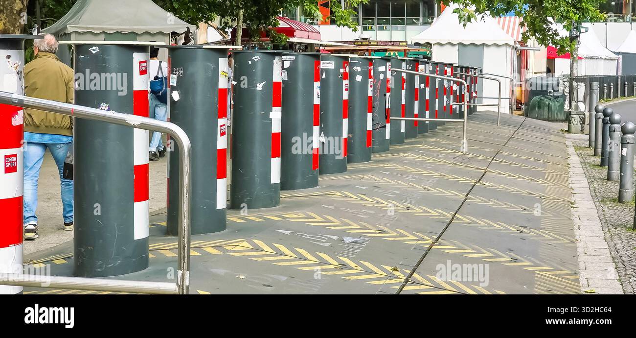 Berlin, Germany - June 11, 2025: Urban street scene features security bollards along a pedestrian walkway with vibrant colors. - Smartphone Captured Stock Image