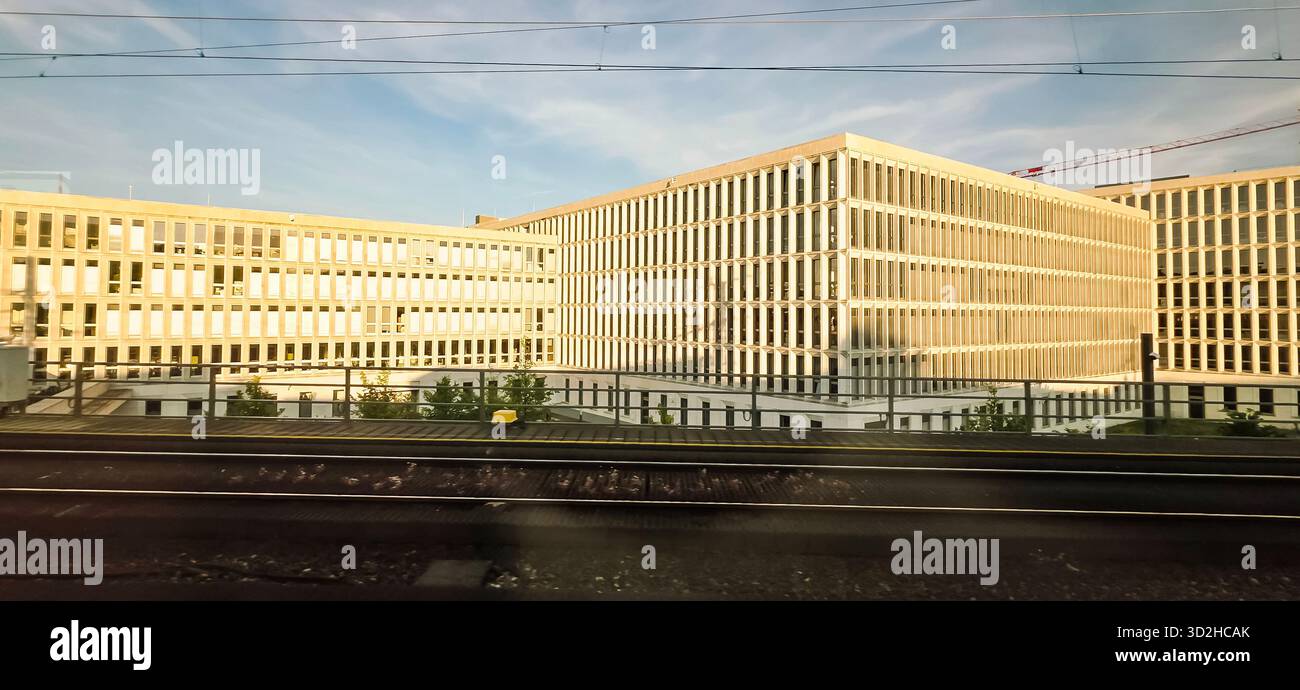 Berlin, Germany - June 13, 2025: Modern architectural structures feature glass facades beside railway tracks. - Smartphone Captured Stock Image
