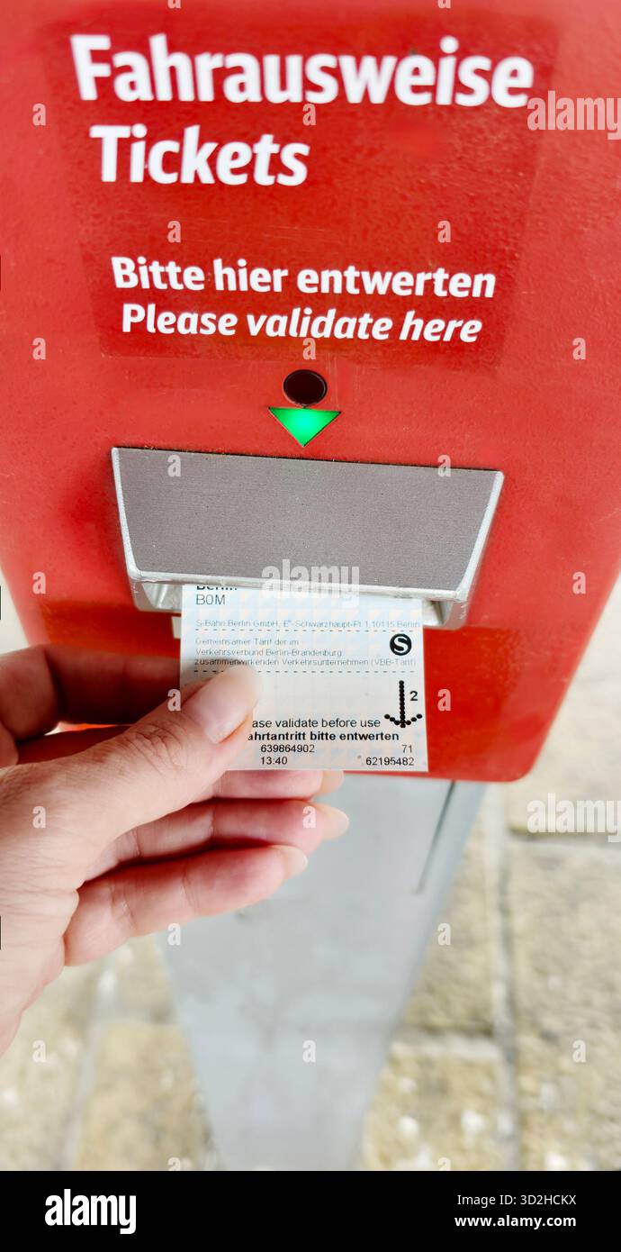 Berlin, Germany - June 27, 2025: . Hand inserting ticket into validation machine at public transport station - Smartphone Captured Stock Image