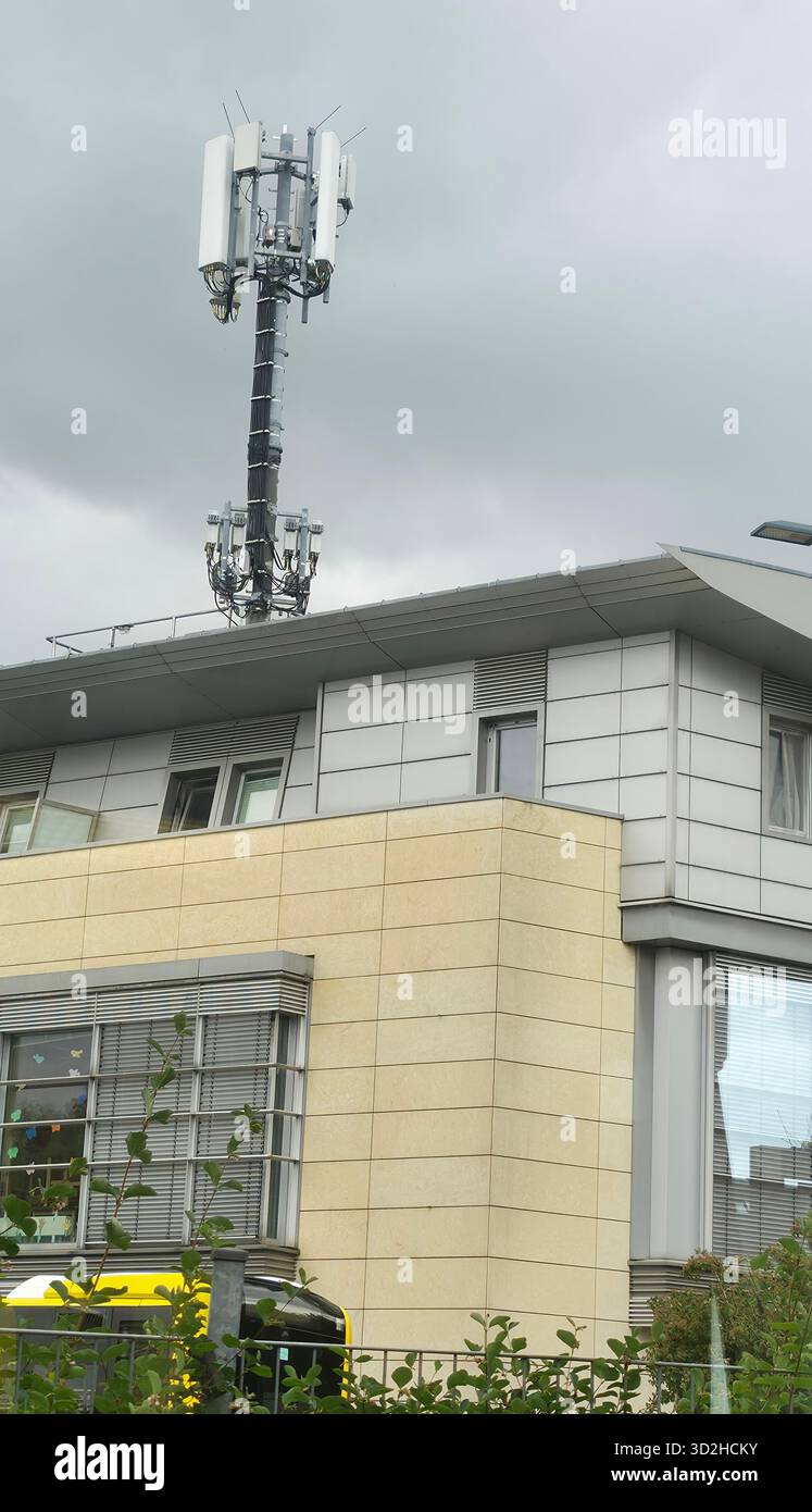 Berlin, Germany - June 27, 2025: . Mobile network antenna is mounted on a modern building under a cloudy sky - Smartphone Captured Stock Image