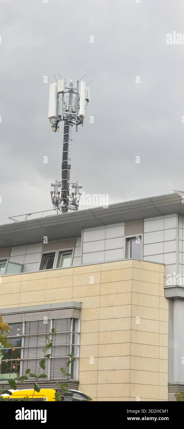 Berlin, Germany - June 27, 2025: . Cell tower is mounted on a contemporary building with a cloudy sky backdrop - Smartphone Captured Stock Image