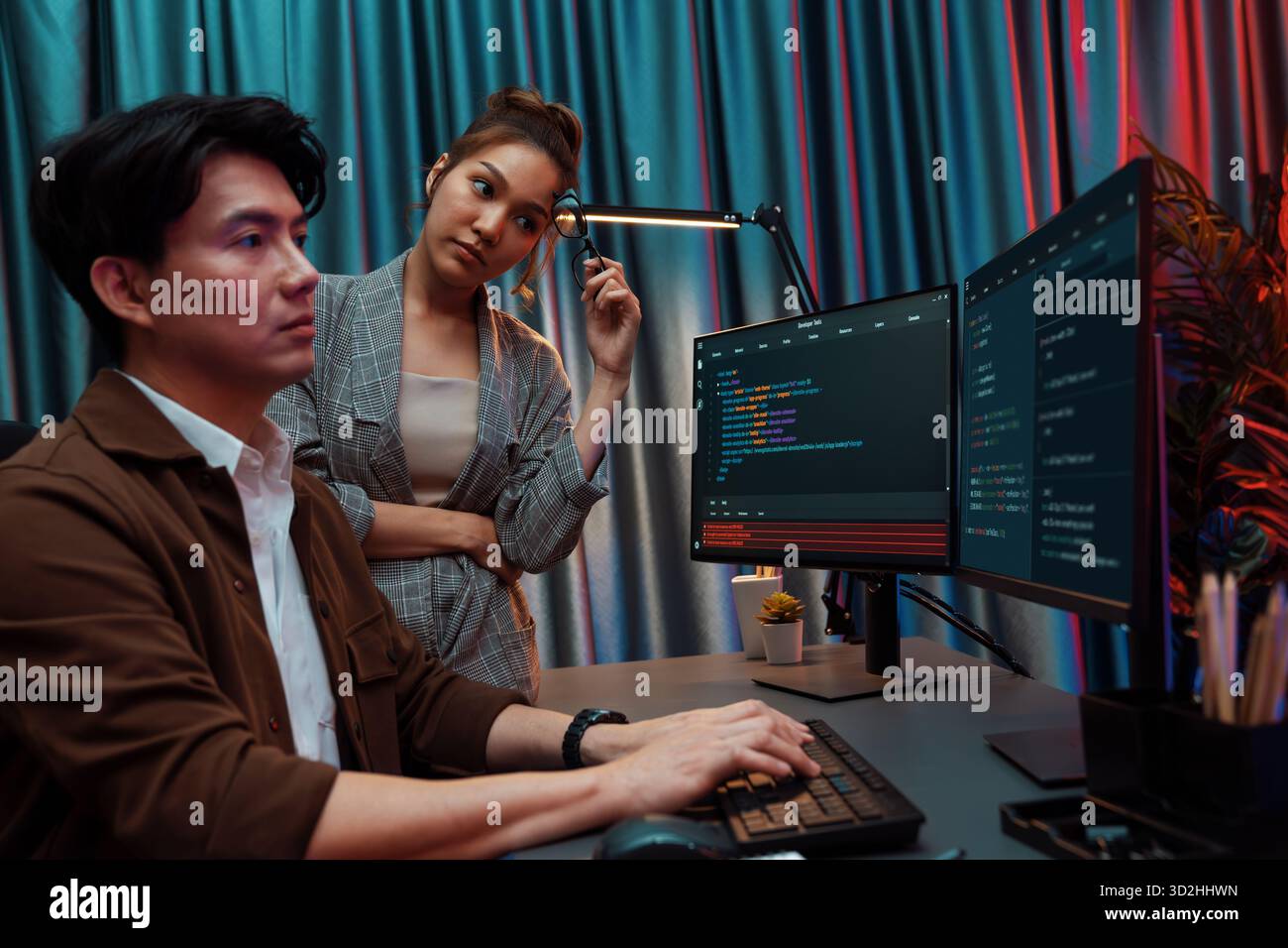 IT developers discussing with point to intelligent website development coder system running data online two screens information technology at neon lig Stock Photo