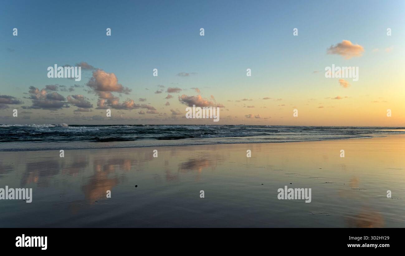 Soft pastel sunset reflected on wet sand at a tranquil tropical beach in Salvador, Bahia, Brazil, taken in October. - Smartphone Captured Stock Image