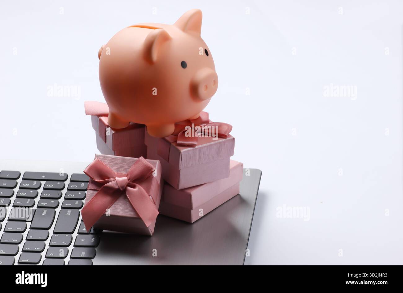 Piggy bank with stack of gift boxes on laptop keyboard closeup Stock Photo