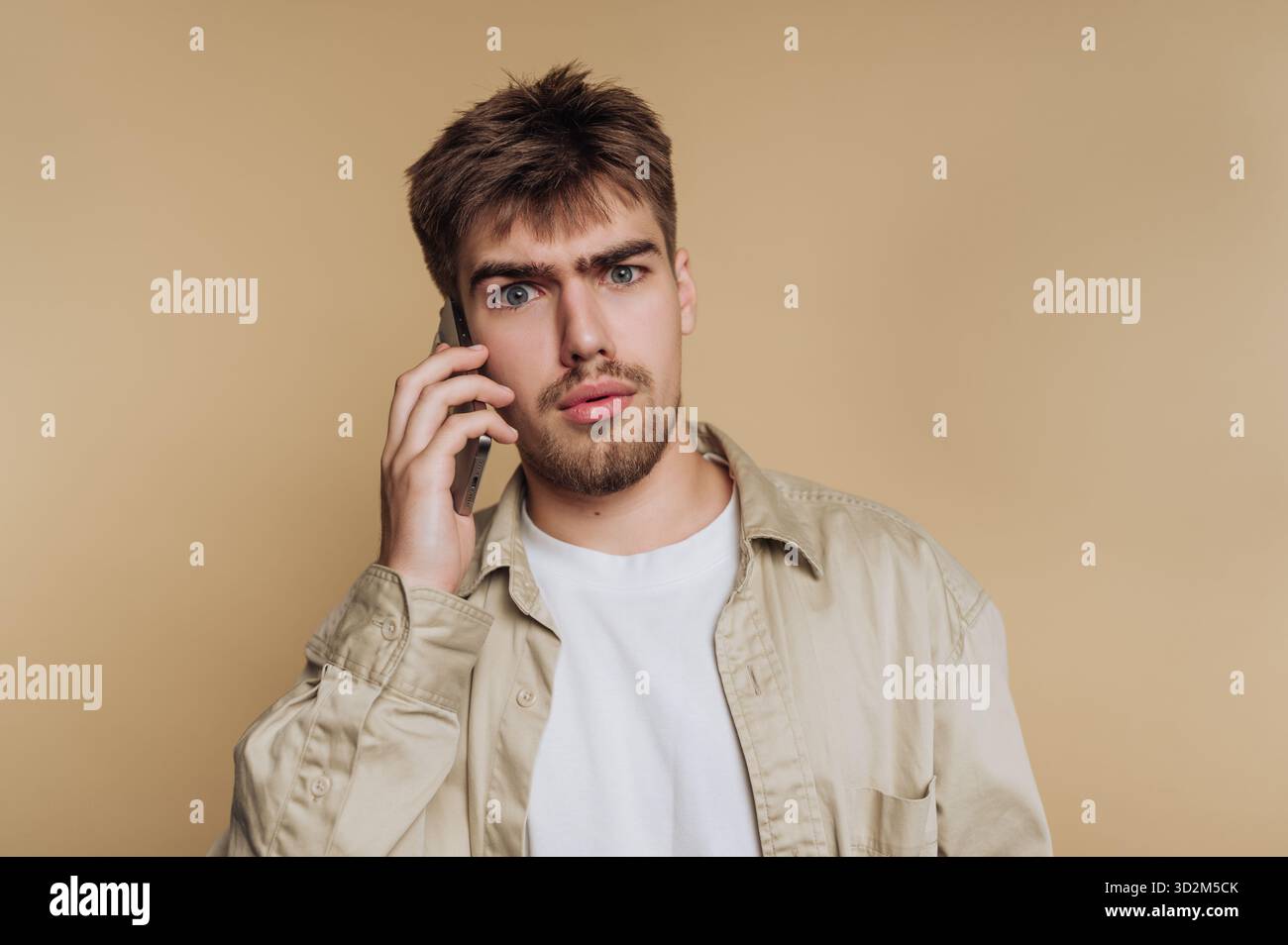 Young man with a surprised expression talking on a smartphone. Stock Photo