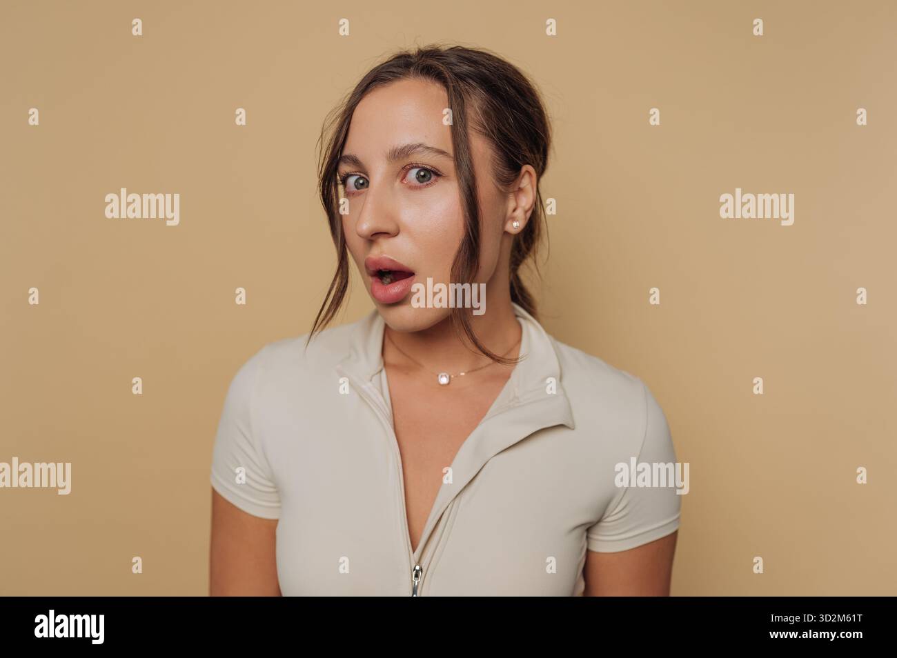 Woman with surprised expression against beige background Stock Photo