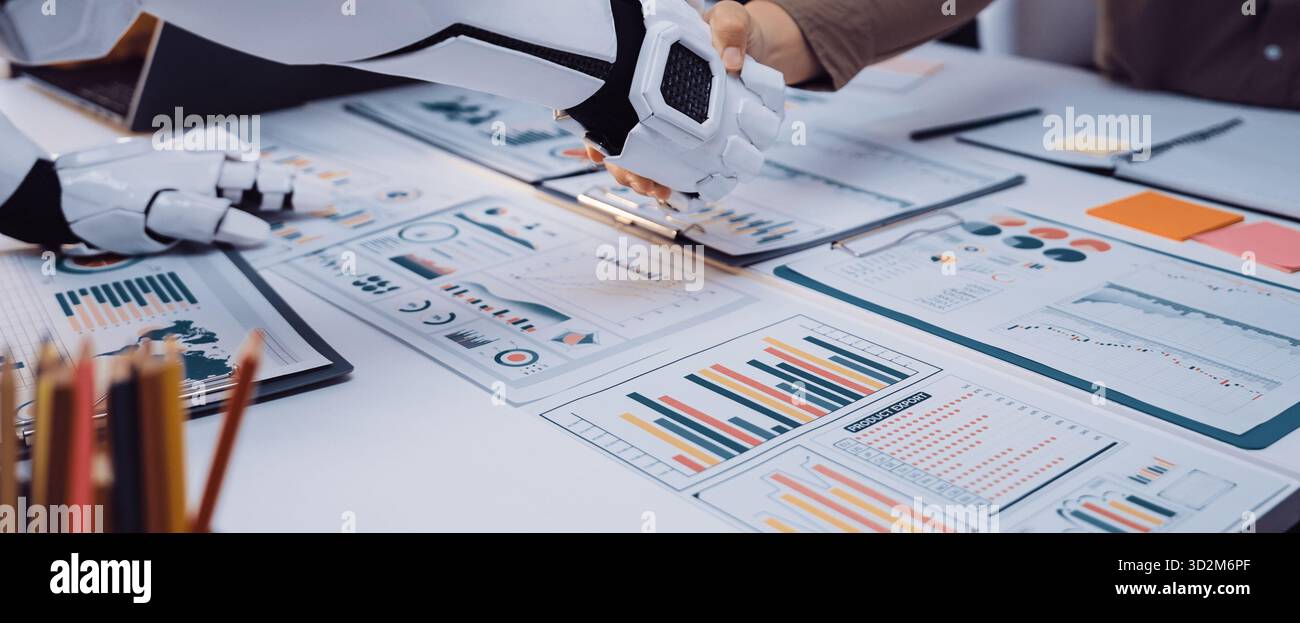 A robot shakes hands with a person in a modern office while surrounded by data charts and documents, symbolizing the future of technology and human co Stock Photo