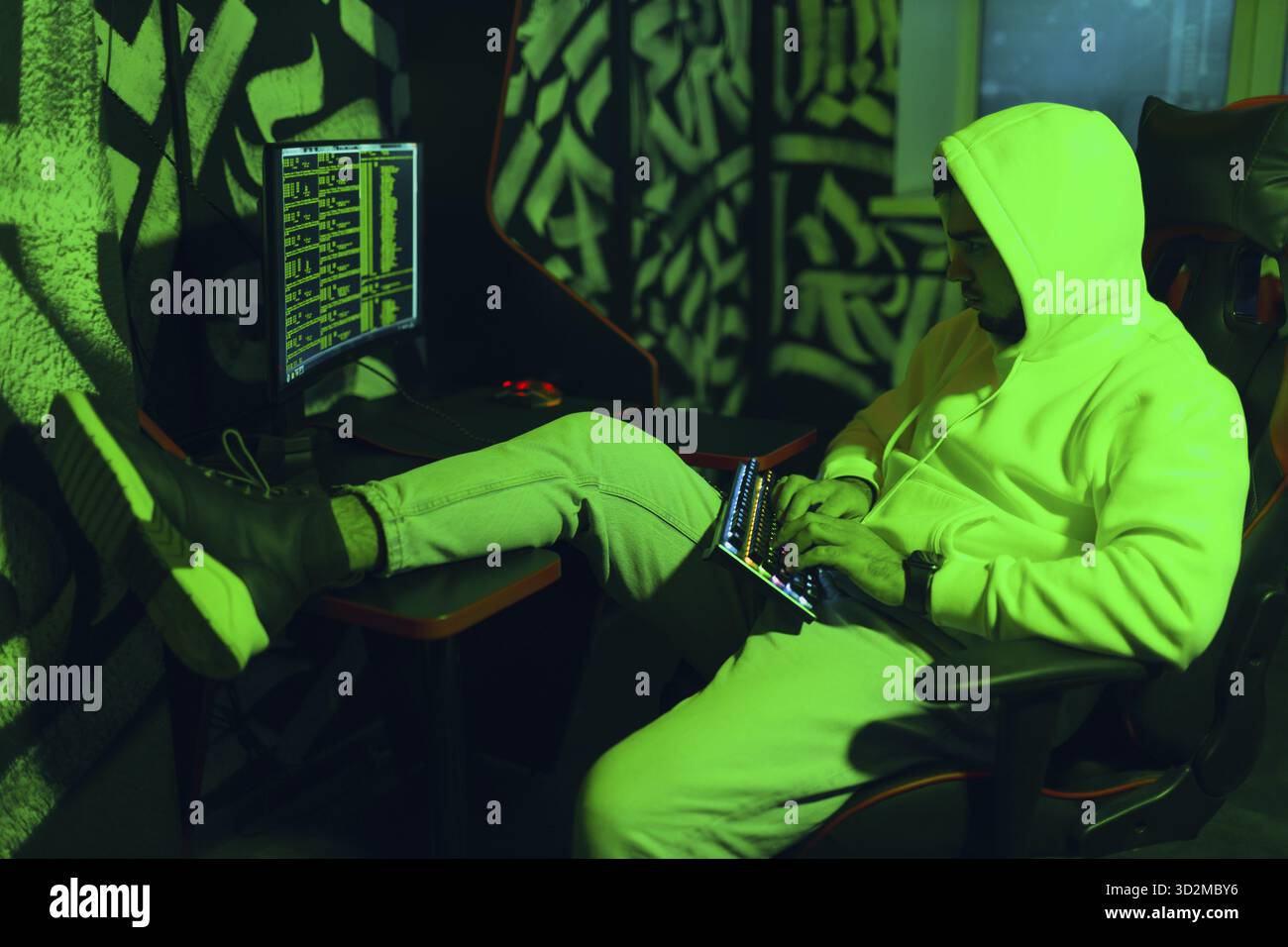 Hacker in hoodie working hacks code site on personal computer Stock Photo
