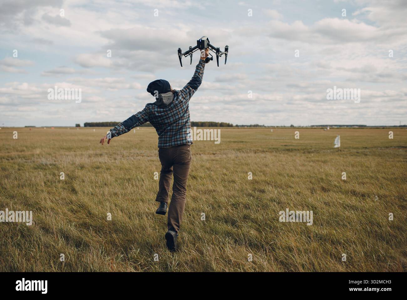 Man pilot holding quadcopter drone in hands at outside field Stock Photo