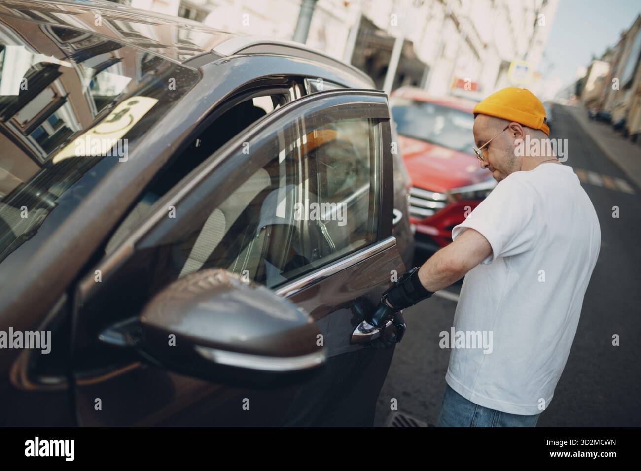 Young disabled man opening vihicle car door with artificial prosthetic hand Stock Photo