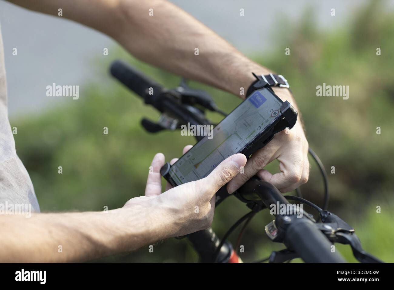 Man planning route using GPS navigation application in mobile phone on his bicycle bike. Plugging device Stock Photo