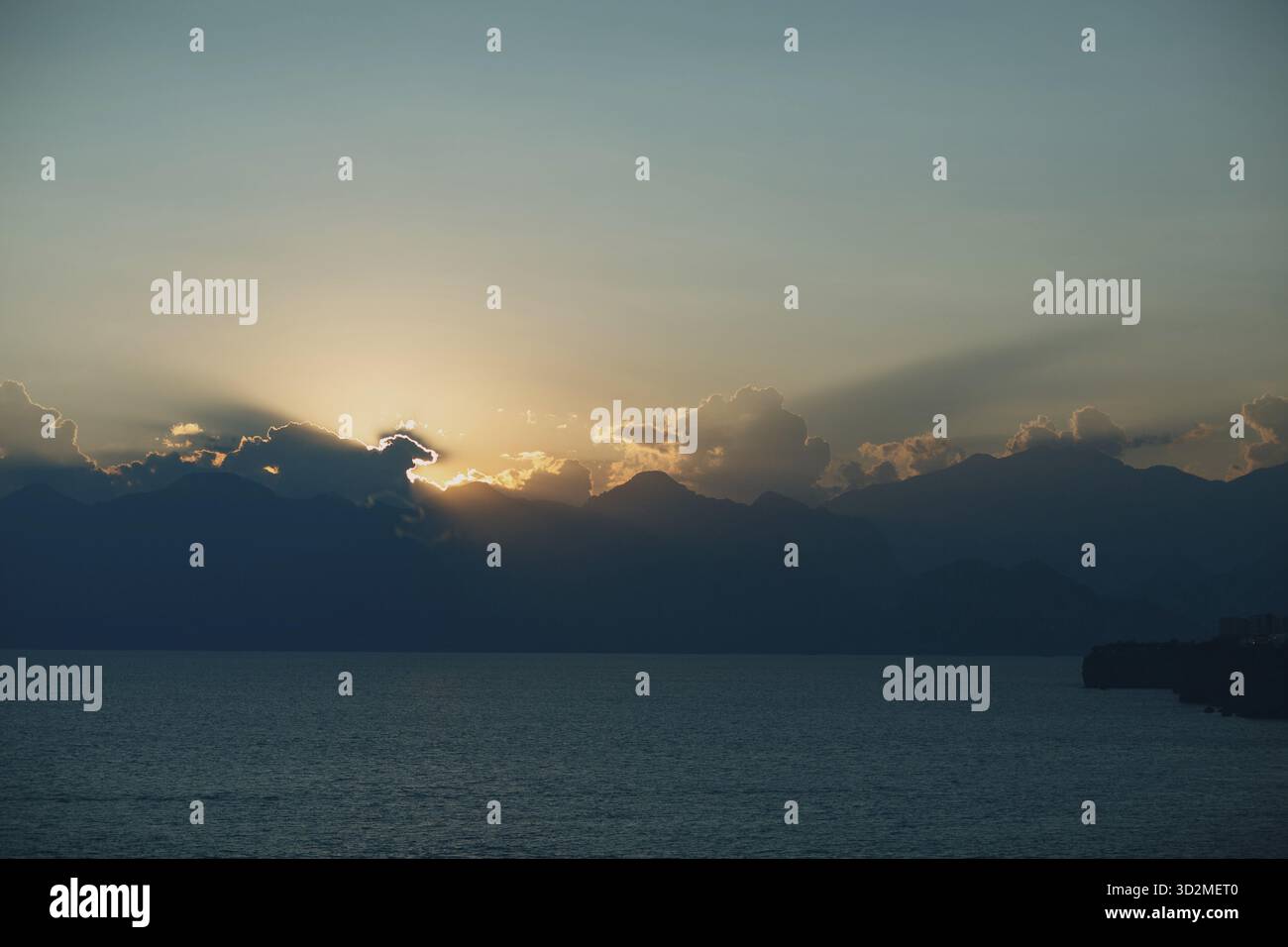 Dramatic sunset rays through cloudy dark sky over the ocean Stock Photo
