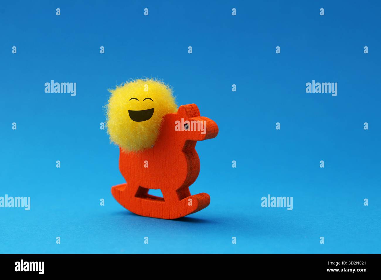 Smiling plush ball riding a rocking wooden horse Stock Photo