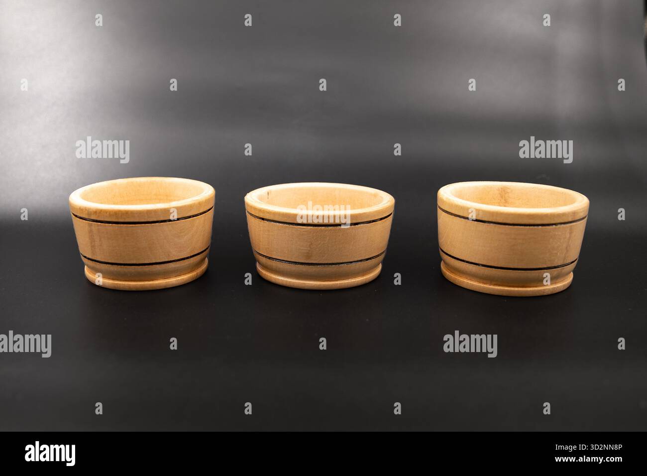 Three small wooden bowls on dark background for minimalistic kitchen design Stock Photo