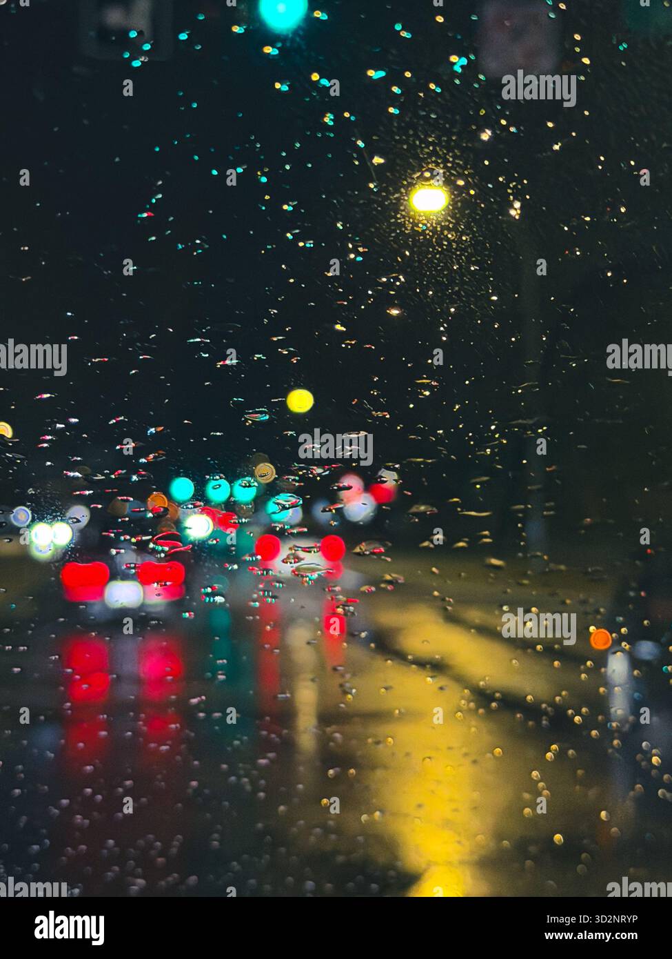 Artistic view of moving cars and city lights through raindrops on a windshield during a rainy night in Edmonton, Alberta, Canada Stock Photo