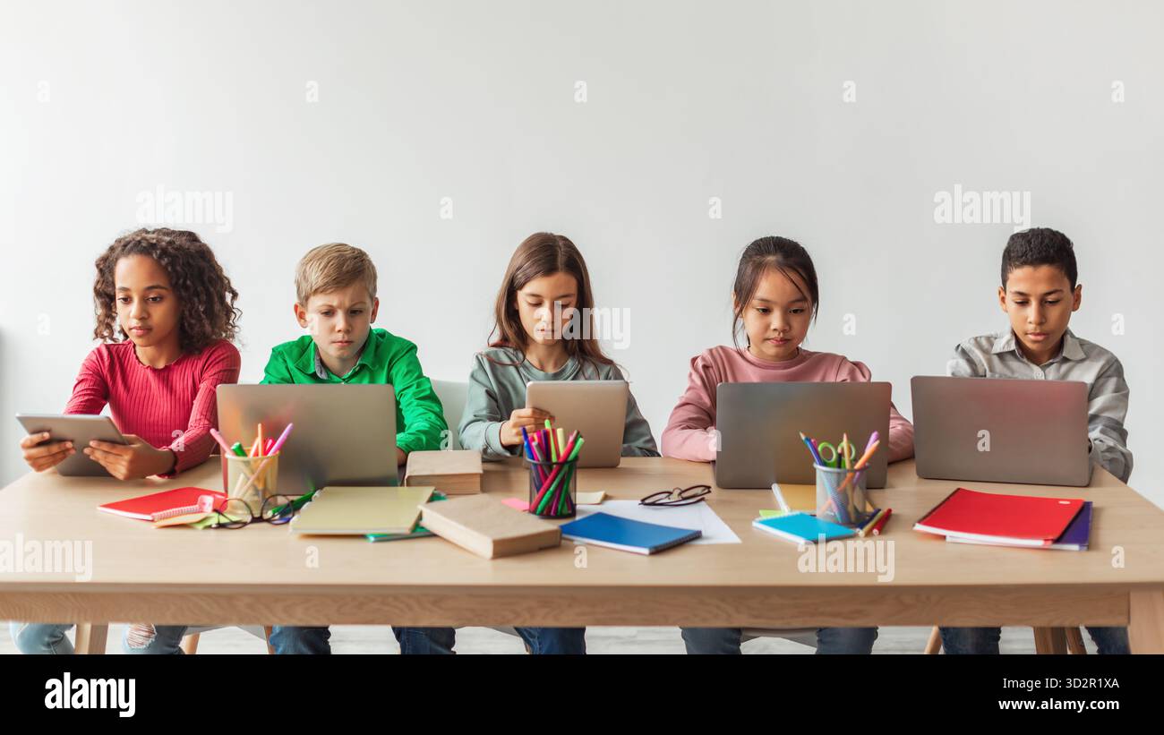Five School Kids Participating in Online Class Using Laptops in a Modern Classroom Setting Stock Photo
